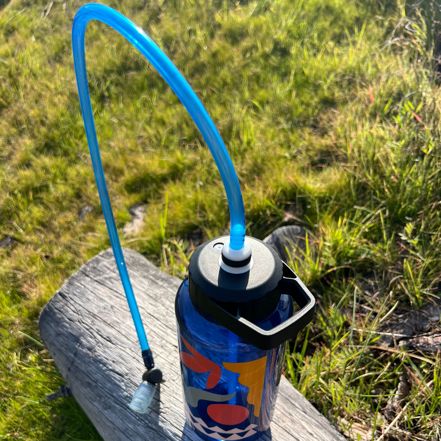 
                  
                    Blue water bottle with a flexible straw on a wooden surface outdoors
                  
                